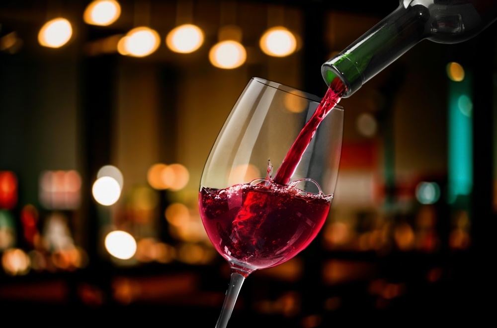 Woman pouring wine from bottle on bar background